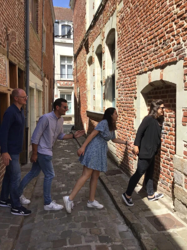 Equipe mimant un passage à travers les murs d'une ruelle pour un défi photo insolite