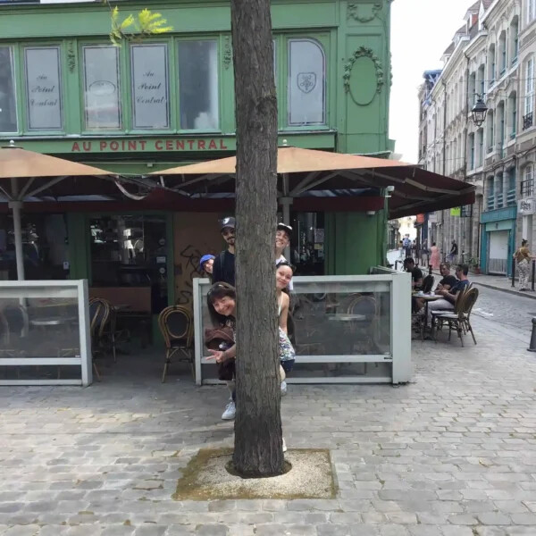 Equipe se cachant derrière un tronc pour un défi photo original d'une Aventure Interactive