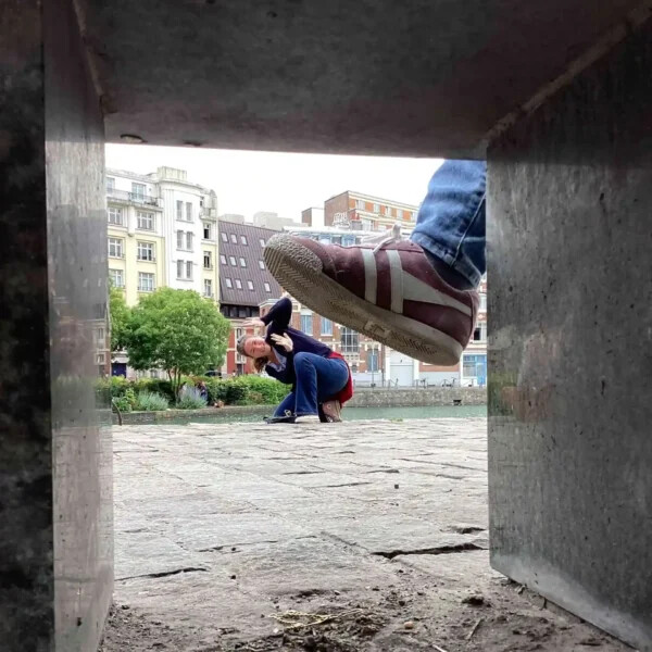 Un pied géant s'apprête à écraser une coéquipière, dans le cadre d'un défi photo en trompe l'oeil