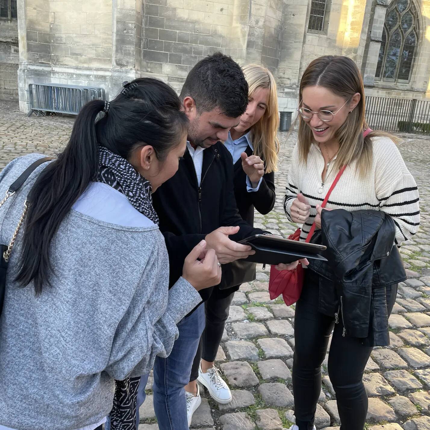 Equipe de collaborateurs qui regardent un téléphone pour poursuivre un rallye urbain