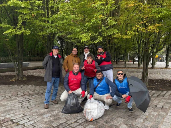 Participants d'une clean walk posant pour un défi photo avec des sacs remplis de déchets