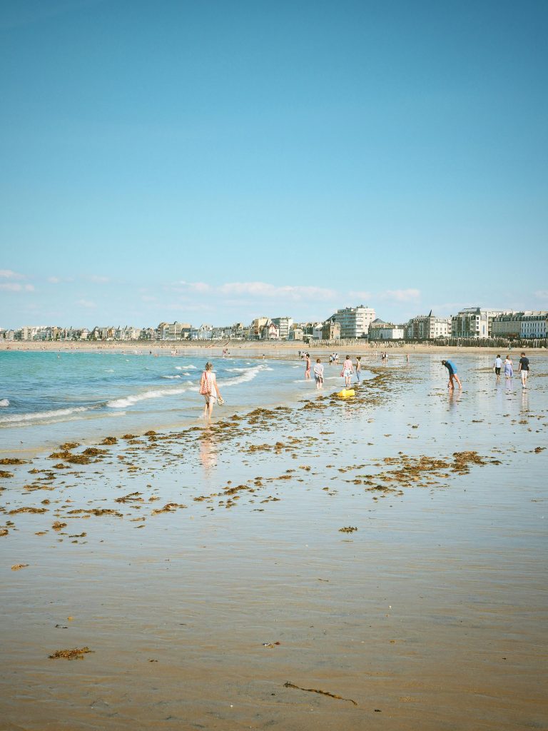 Photo de la plage à Saint Malo avec des adultes et des enfants qui jouent / marchent au loin