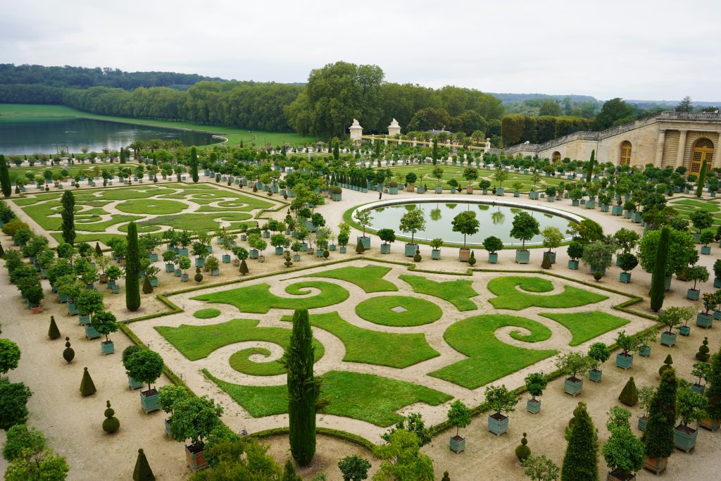 Photo des jardins de Versailles avec le jardin bien vert et les plans d'eau