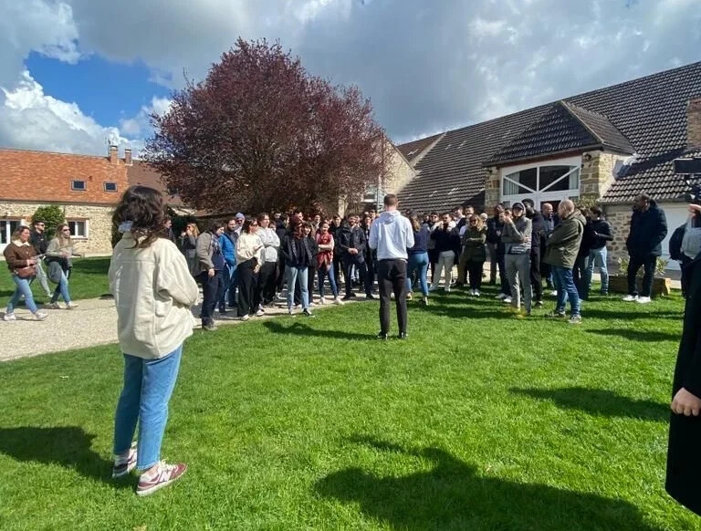 Une animatrice réalise un brief de groupe en extérieur, pour un grand challenge RSE